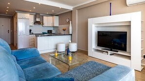 A modern living room with a blue sofa, a glass coffee table, and a flat-screen TV mounted on a white wall. - Altea Bahia - Altea, Costa Blanca (Altea)