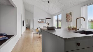 Uma cozinha moderna com uma ilha grande, área de refeições e vista para o exterior.