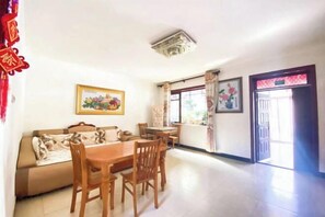 A dining area with a table and chairs, a sofa, and a framed picture on the wall.