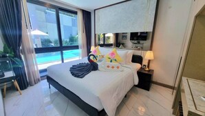 A hotel room with a large bed, a TV, and a view of a swimming pool. - Bo205 - 1 Bdr Condo With Pool Access Ao Nang Beach (Krabi)
