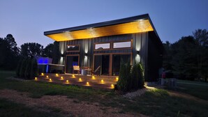 Uma casa moderna com um amplo deck, grandes janelas e uma banheira de hidromassagem.