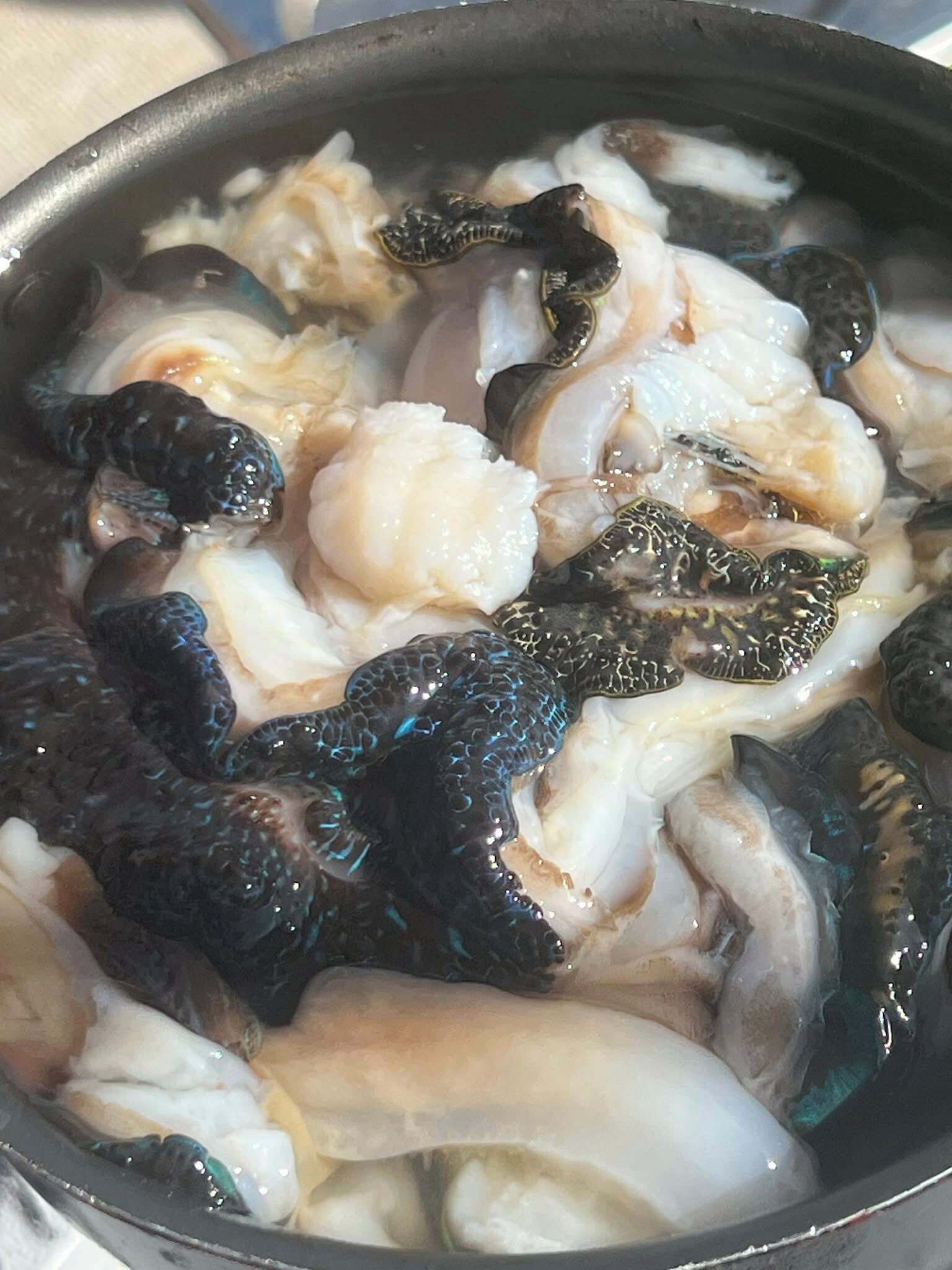 Une poêle contenant divers fruits de mer, notamment des crevettes et des calamars, en cours de cuisson.