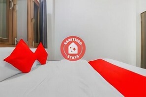 Ein Hotelzimmer mit einem Bett, einem roten Kopfkissen und einem runden Logo an der Wand.
