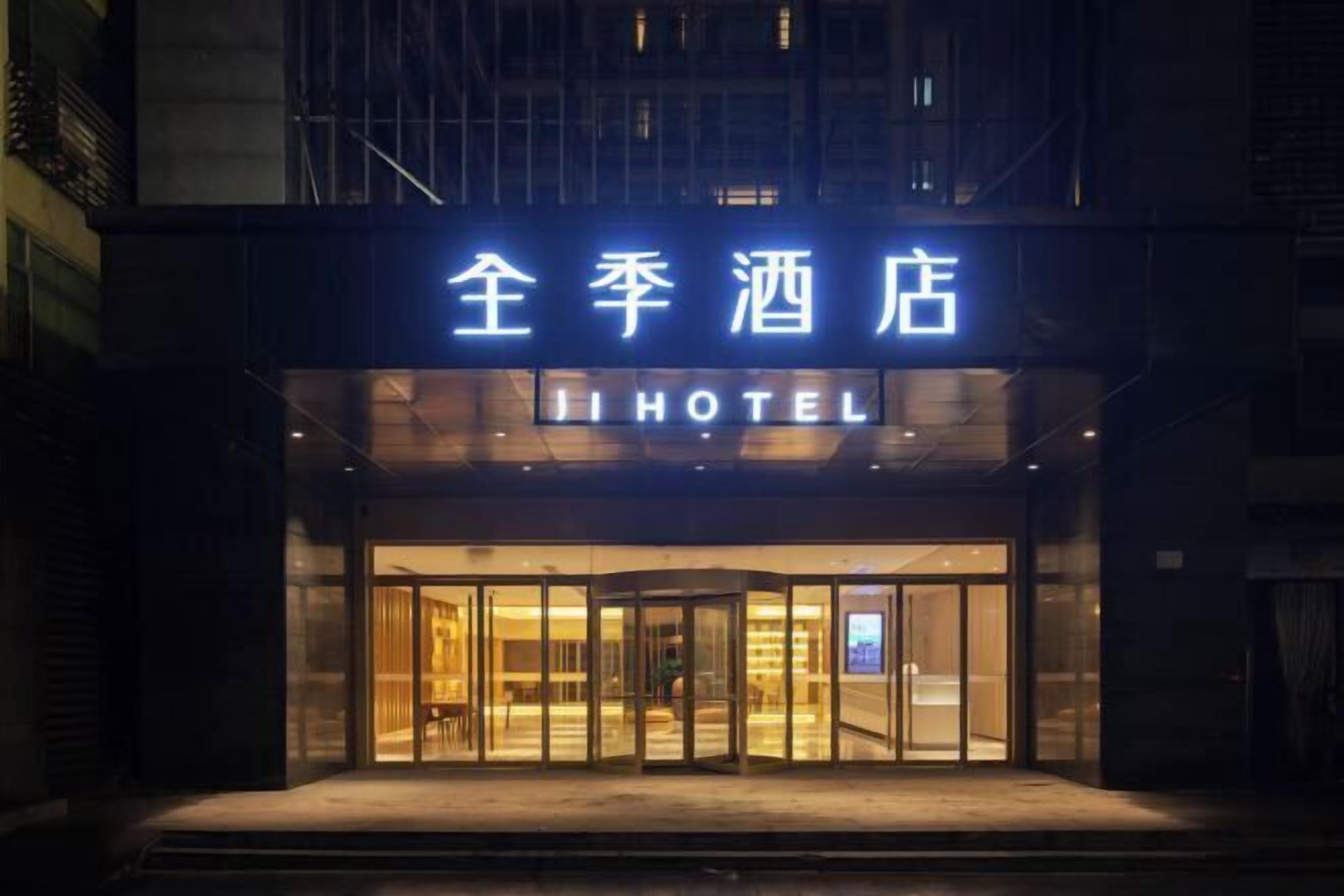 L’entrée d’un hôtel, avec une porte en verre et une enseigne en chinois et en anglais.