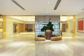 A spacious lobby with a large potted plant, seating areas, and a glass wall. - JI Hotel (Guangzhou Huangpu Nangang Wanda) (Guangzhou)