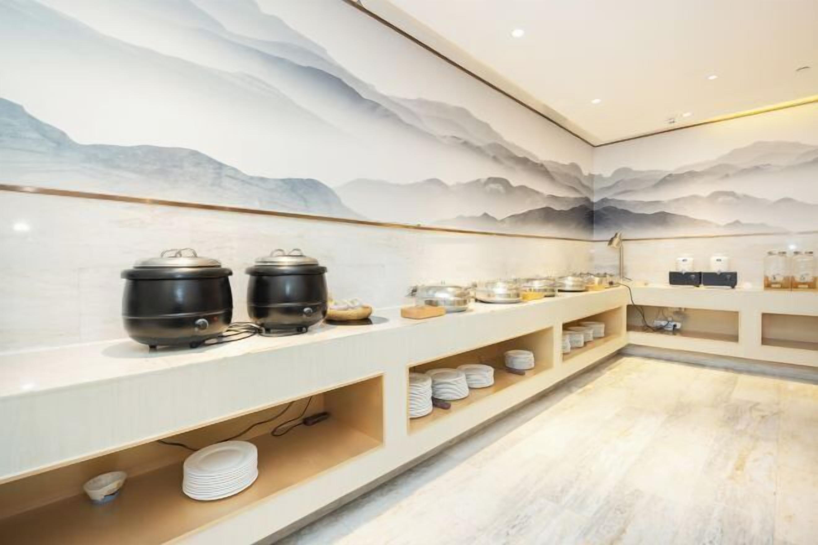 A buffet setup with multiple serving stations, including hot and cold food options, and a decorative wall mural.