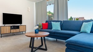 A modern living room with a sectional sofa, a flat-screen TV, and a wooden coffee table. - Holiday Home 'Architektenhaus C1 Mit Seesicht' with Lake View, Private Terrace and Wi-Fi (Öhningen)