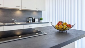 A modern kitchen with a built-in stove, a sink, and a fruit bowl on the countertop. - Holiday Home 'Architektenhaus C1 Mit Seesicht' with Lake View, Private Terrace and Wi-Fi (Öhningen)