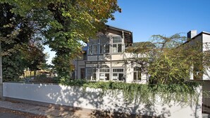 A two-story building with large windows, a white exterior, and a tree in the foreground. - Villa 'Effi-Briest-' with Mountain View, Private Terrace and Wi-Fi (Ostseebad Heringsdorf)