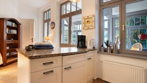 A kitchen with a built-in oven, a coffee maker, and a window with a view of greenery. - Villa 'Effi-Briest-' with Mountain View, Private Terrace and Wi-Fi (Ostseebad Heringsdorf)