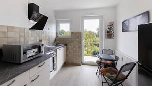 Eine moderne Küche mit Einbau-Mikrowelle, einem kleinen Fenster und einem Balkon mit Tisch und Stühlen.