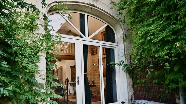 A traditional arched doorway with a glass door, surrounded by lush greenery. - Mas Provençal à 10 Minutes de Nîmes. Animaux de Compagnie Acceptés ! (Générac)