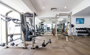 Un gimnasio con diversos equipos de ejercicio, incluyendo máquinas de pesas y pesas libres.