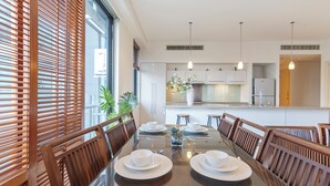 Un espace repas moderne avec une table en verre, des chaises en bois et une vue sur la cuisine.