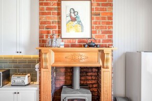 Traditional kitchen with a brick wall, wood stove, and framed artwork above.