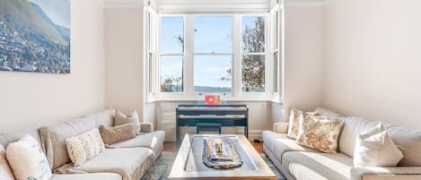 A living room with two sofas, a coffee table, and a view of a mountain through a large window.