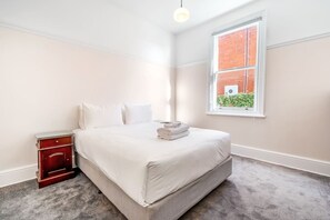 Relax in a spacious room with a large bed, nightstand, and window offering a view of the surrounding area.
