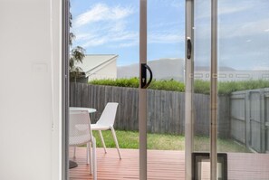 A sliding glass door leading to an outdoor patio with a white chair and a table. - Sunny Retreat in Kingston Beach (Kingston Beach)