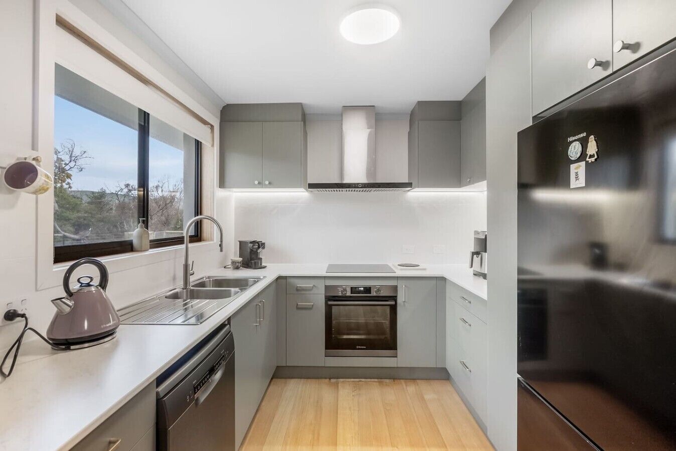 A compact kitchen with a dishwasher, oven, and stainless steel refrigerator.