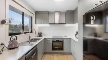 A compact kitchen with a dishwasher, oven, and stainless steel refrigerator.