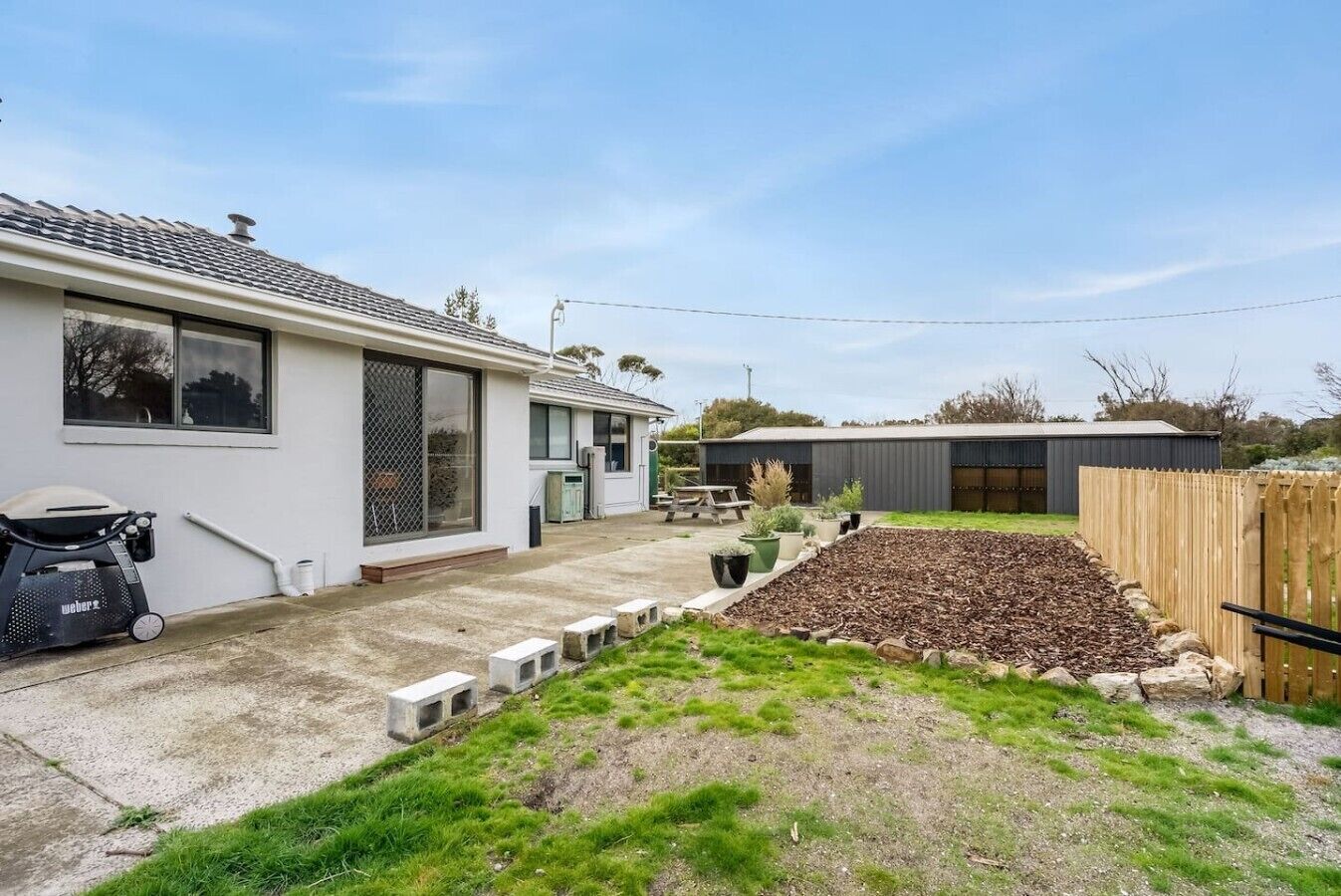 A residential property with a house, a garden with a raised bed, a barbecue, and a shed.