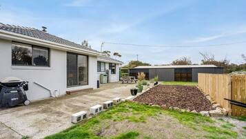 A residential property with a house, a garden with a raised bed, a barbecue, and a shed.