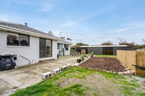 A residential property with a house, a garden with a raised bed, a barbecue, and a shed. - Peaceful Beachside Home (Clifton Beach)