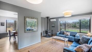 Un salón amplio con un sofá azul, una mesa de centro y una chimenea.