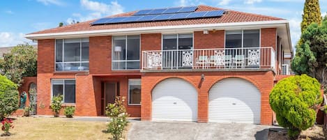 A two-story house with a balcony, solar panels, and a garage.