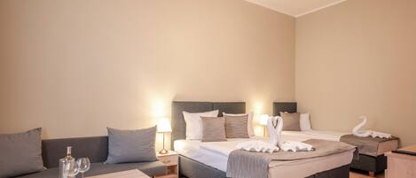 A hotel room with a bed, a sofa, a coffee table, and a lamp.
