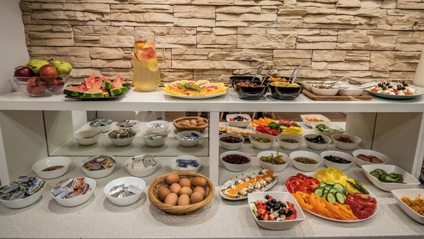 Un bufé con diversos alimentos y un fondo de pared de piedra.