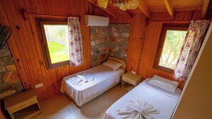 Ein Zimmer in einer Holzhütte mit zwei Betten, einer Steinwand und einem kleinen Holztisch.
