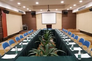 A conference room with a long table, chairs, water bottles, and a projector screen. - Yuheng Hotel Foshan (Foshan)