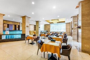 A restaurant with tables and chairs, a counter, and a decorative wall. - Yuheng Hotel Foshan (Foshan)