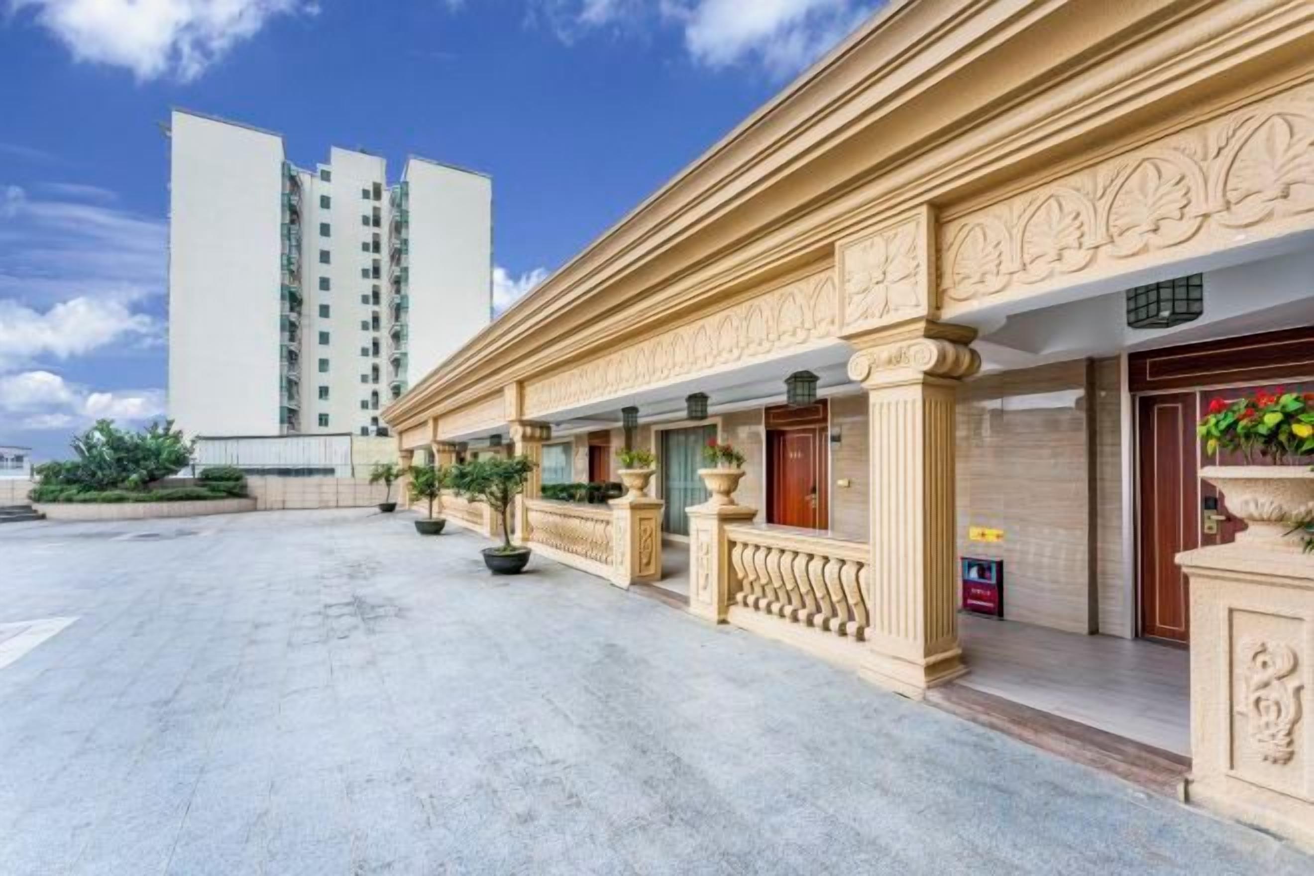 A hotel with a classical facade, a courtyard, and a tall building in the background.