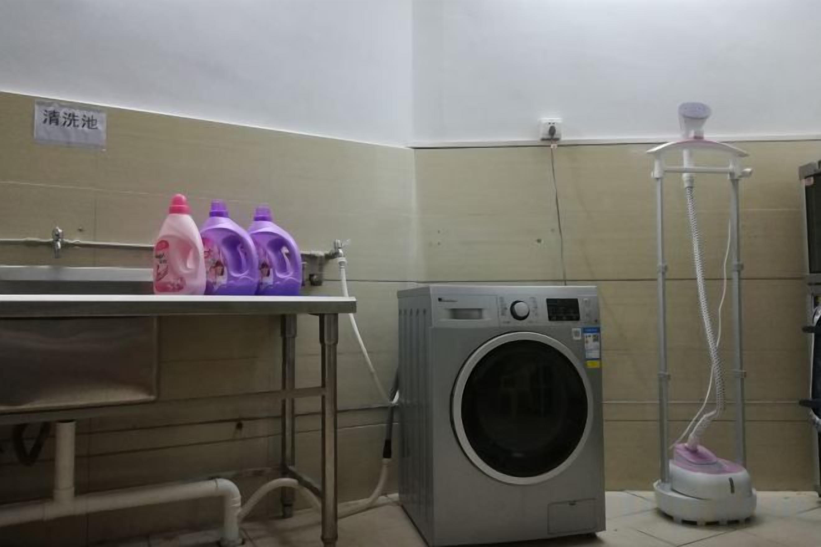 A public washroom with a washing machine, a dryer, and a water fountain.