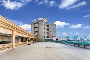 A hotel courtyard with a large building, a pool, and a clear sky. - Yuheng Hotel Foshan (Foshan)