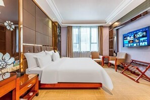 A hotel room with a large bed, a TV on the wall, a desk, and a chair. - Yuheng Hotel Foshan (Foshan)