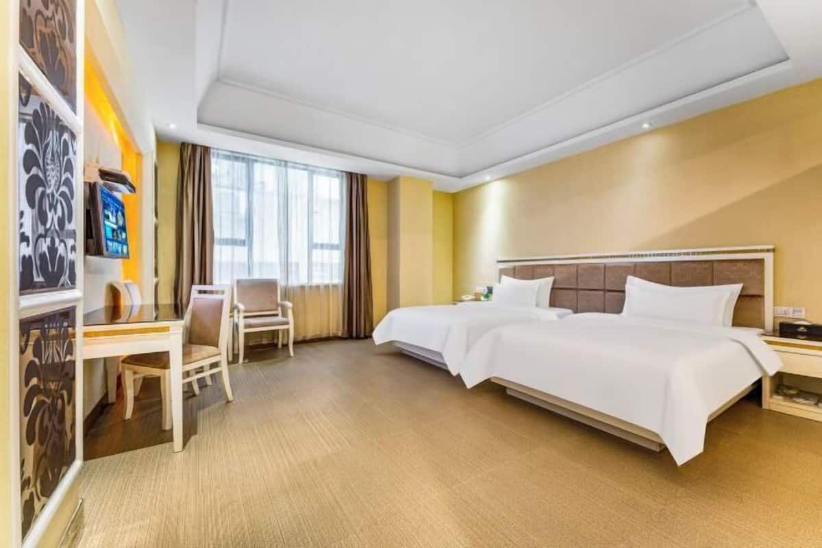A hotel room with a bed, a desk, a chair, a TV, and a window.