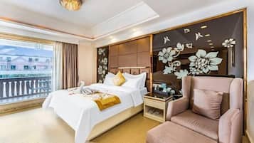 Una habitación de hotel con cama, sillón, mesita de noche, un diseño decorativo en la pared y vistas a través de una ventana.