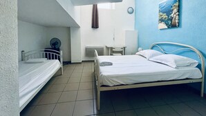 A room with two beds, a desk, a chair, a radiator, and a painting on the wall. - Balaena (Marseille)