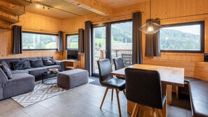 Ein modernes Interieur mit Holzbalkendecke, einer Couch, einem Esstisch und Stühlen.