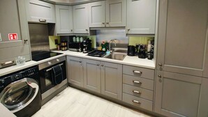 Una cucina compatta con mobili grigi, un lavello in acciaio inox e una lavatrice integrata.