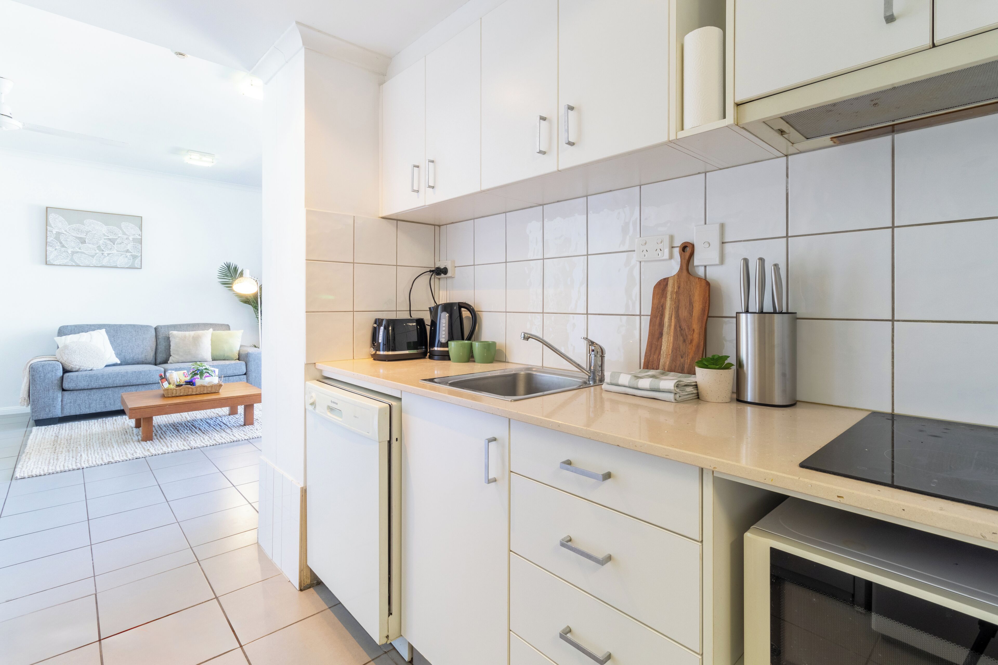 Une cuisine moderne avec des meubles blancs, un lave-vaisselle, un évier et un four à micro-ondes.