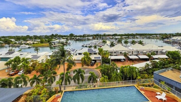 A marina with boats, a swimming pool, and several buildings with solar panels.
