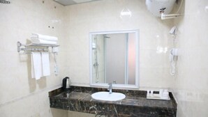 Une salle de bain avec un comptoir en marbre, un lavabo blanc, un miroir et un porte-serviettes.