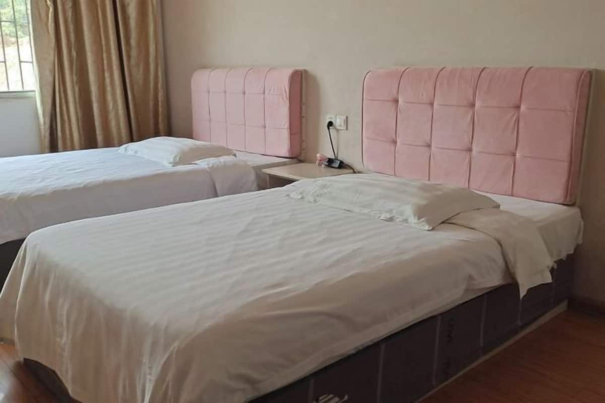 A hotel room with two beds, a bedside table, and a window with curtains.