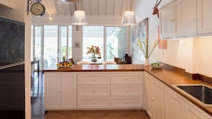 A kitchen with white cabinets, a wooden countertop, a gas stove, and pendant lights. - Villa Karina Umalas (Kerobokan)