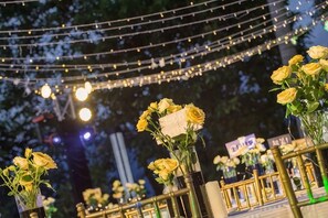 Een buitenomgeving met lichtjes en gele bloemen in vazen.