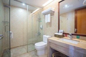 A modern bathroom with a glass shower enclosure, a toilet, and a sink with a mirror above it.